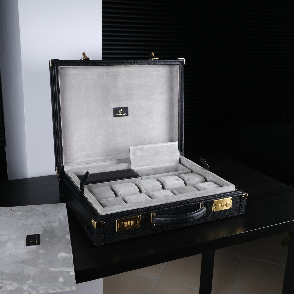 OFL black leather watch case, open with a watch collection inside, on a desk
